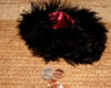 Black fur pouch with a red interior on a textured brown surface, with coins in the foreground.