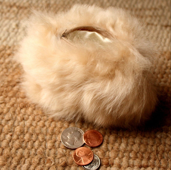 White fur pouch with coins on a textured brown surface