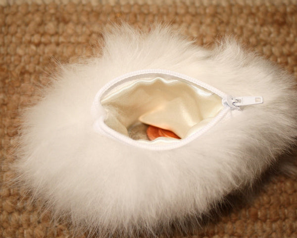 White fur pouch with a zipper on a beige carpet