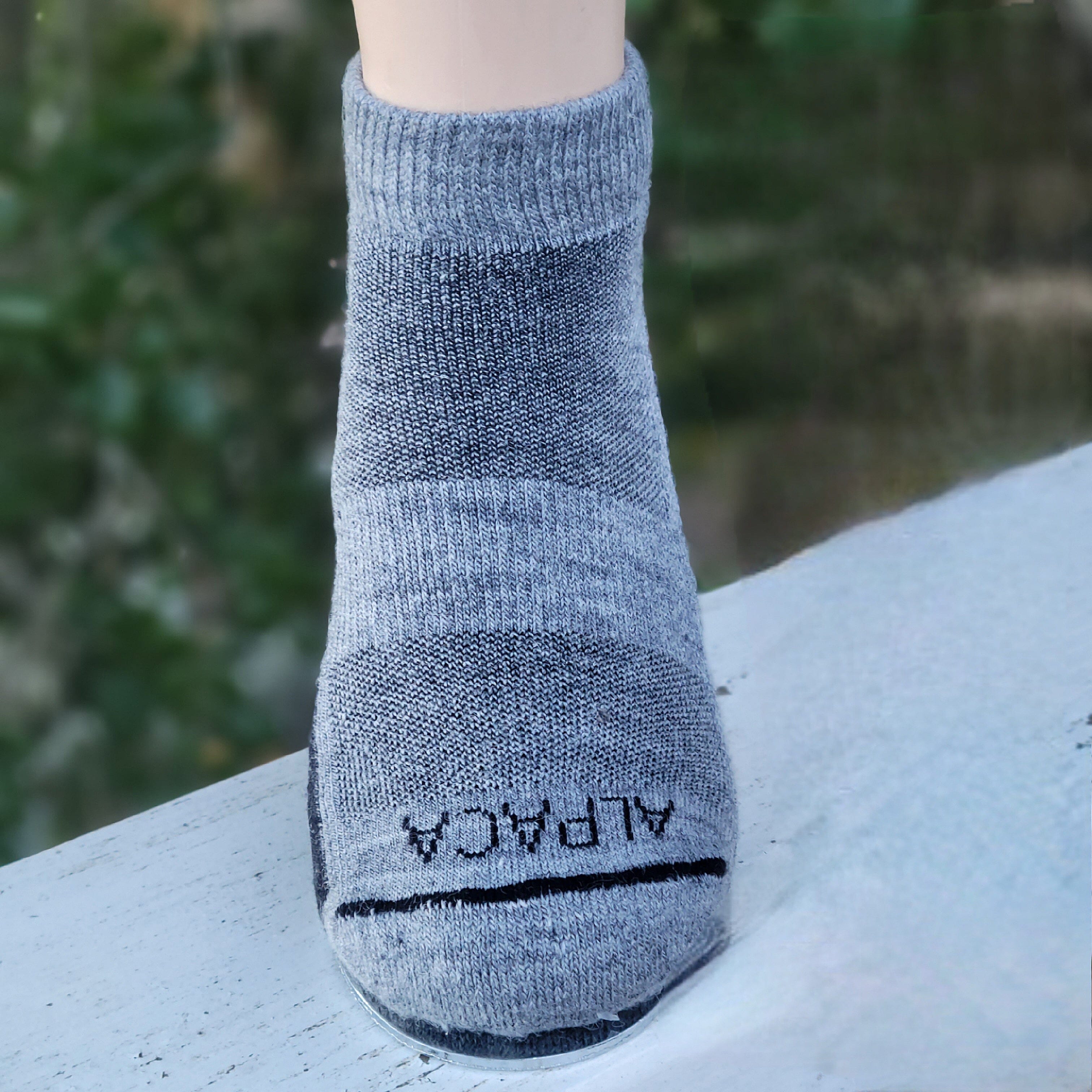 Gray alpaca sock on a mannequin foot with a blurred green background