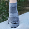 Gray alpaca sock on a mannequin foot with a blurred green background