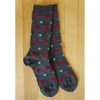 Pair of gray socks with red and white heart patterns on a wooden floor.