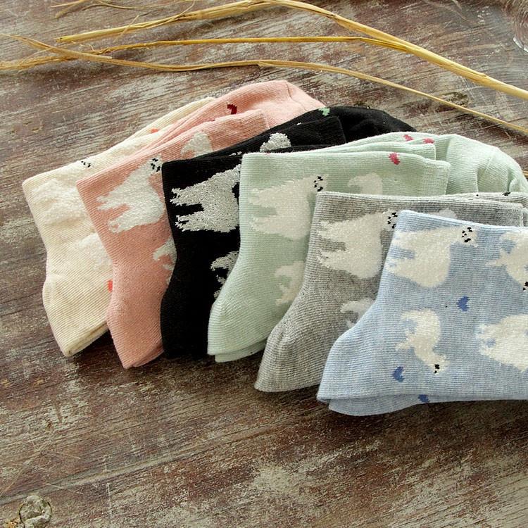 Set of folded baby blankets with cloud patterns on a wooden surface