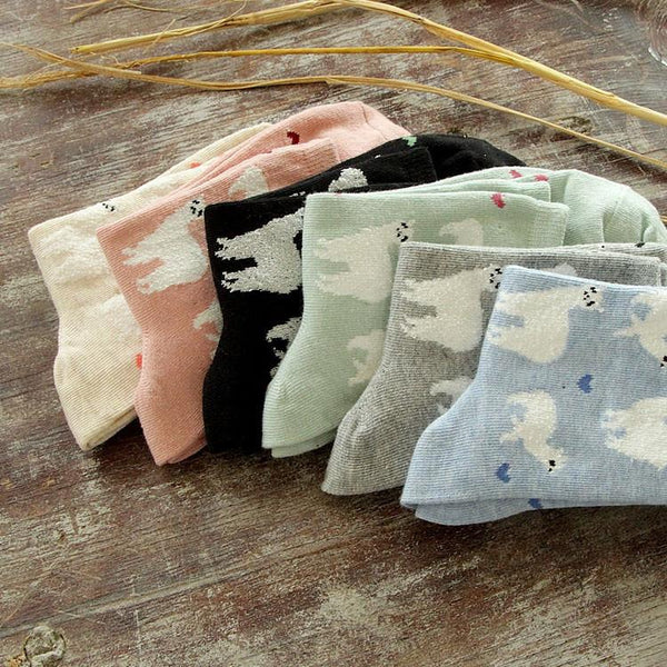 Set of folded baby blankets with cloud patterns on a wooden surface