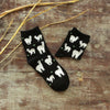 Black socks with white llama designs on a wooden surface