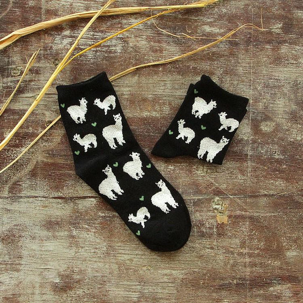 Black socks with white llama designs on a wooden surface