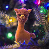 Plush llama toy hanging on a decorated Christmas tree with colorful lights.