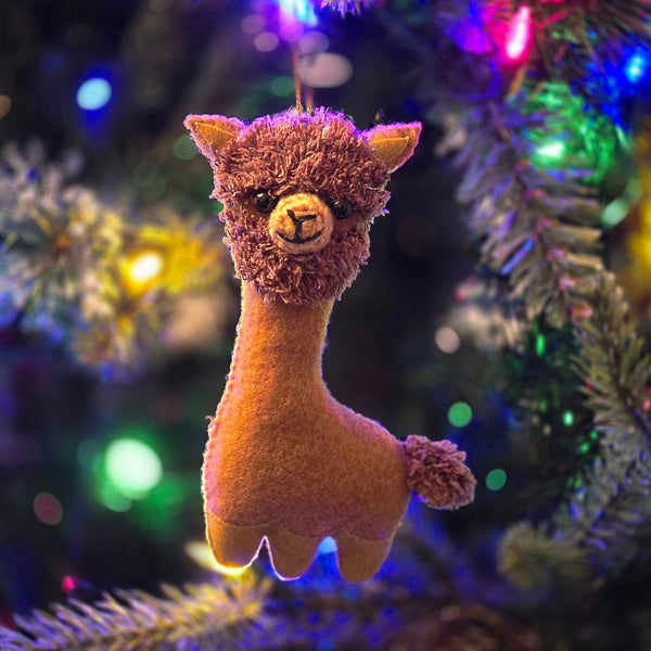 Plush llama toy hanging on a decorated Christmas tree with colorful lights.