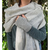 Person wearing a large gray alpaca scarf with greenery in the background