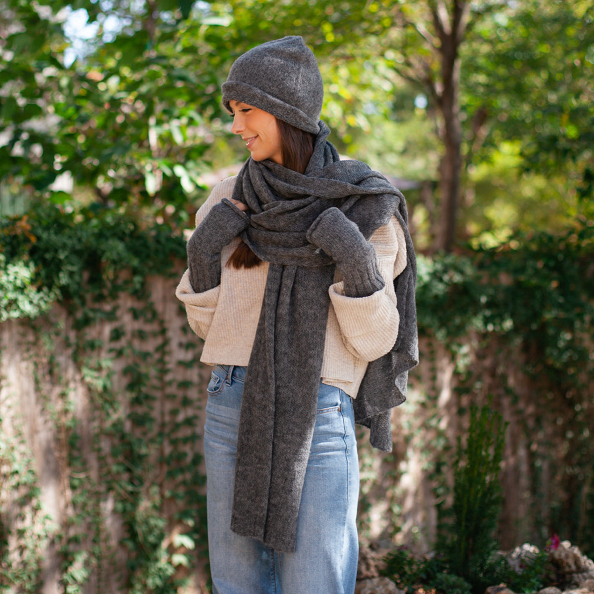 Woman wearing a gray knit hat and scarf in a garden setting