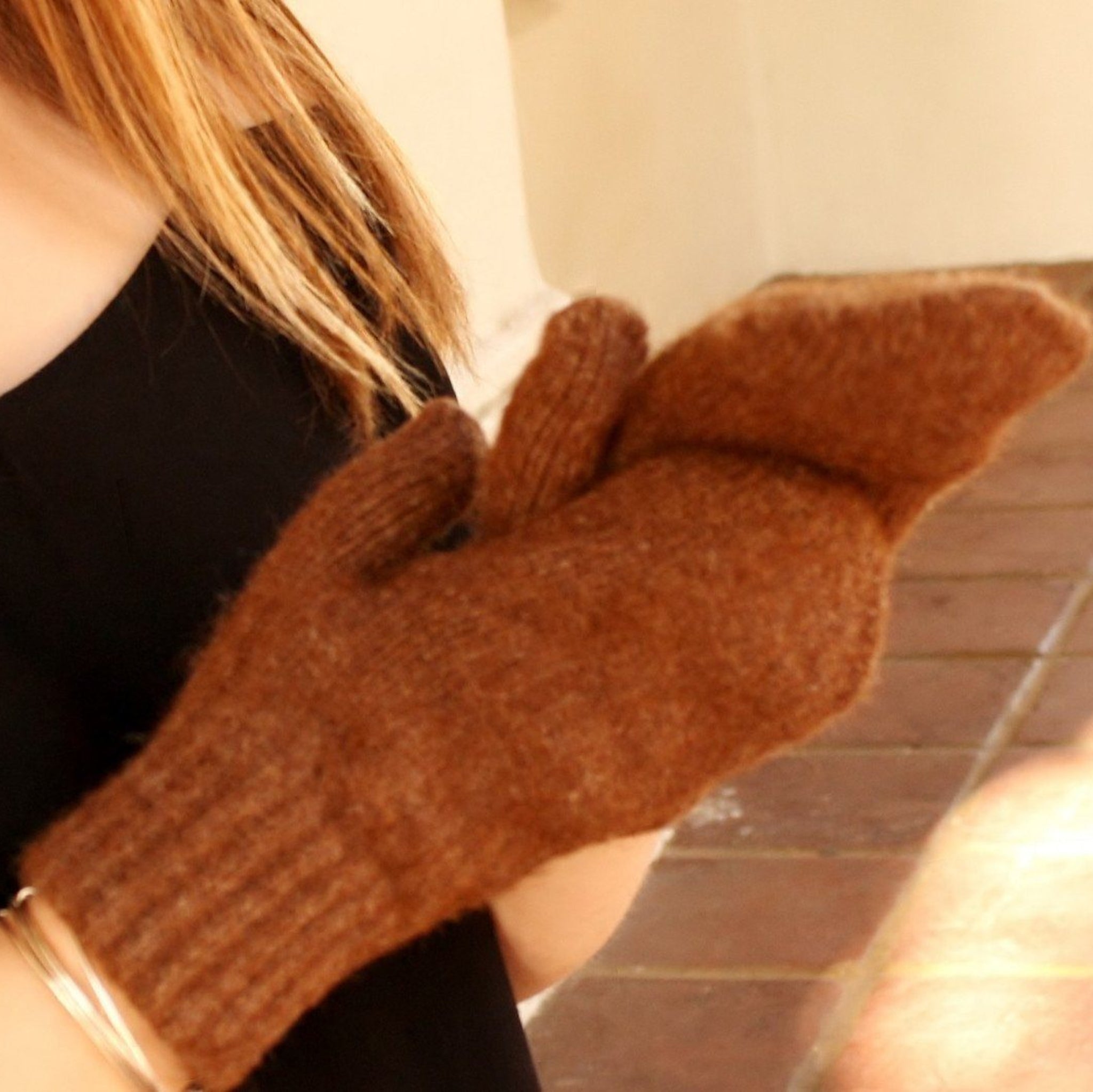 Person wearing a brown knitted glove on a blurred background