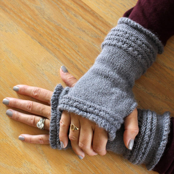 Gray knitted fingerless gloves on a wooden surface