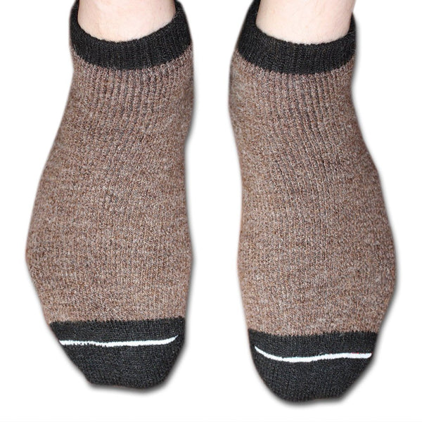 Brown socks with black cuffs and toes on a white background. Stay cozy with AlpacaTrax Gripper Slipper Socks – ultra-warm, non-slip alpaca wool socks for men & women. Breathable, odor-free, durable, and machine washable. Perfect house slipper alternative.