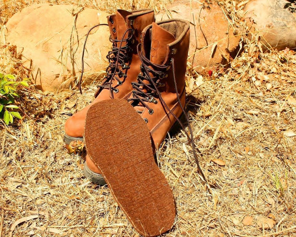 Brown leather boots with a focus on the sole on a natural ground background