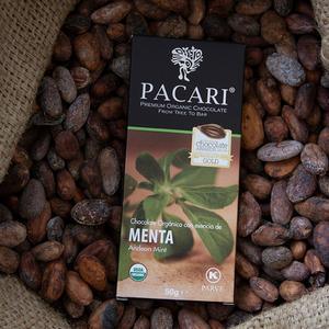Pacari Menta chocolate bar surrounded by cocoa beans on a rustic background