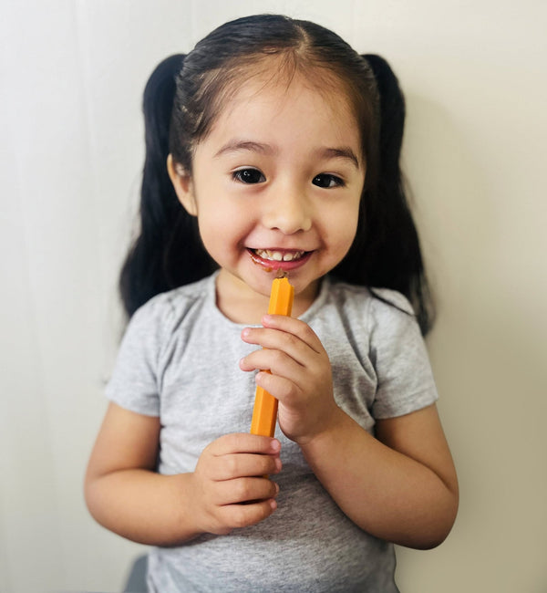 Child holding a carrot against a plain background