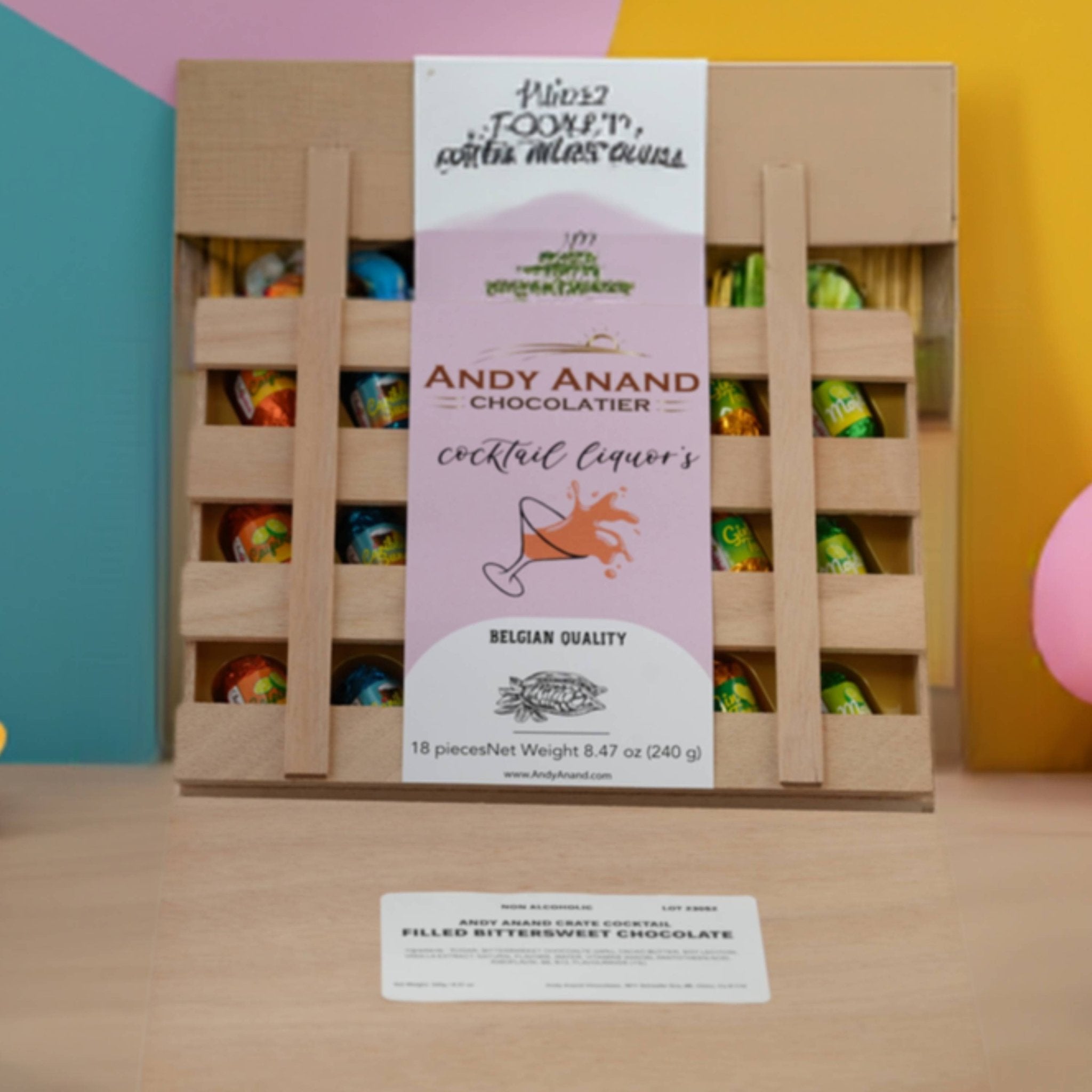 Andy Anand Chocolatier chocolate assortment in a wooden crate with colorful chocolates.