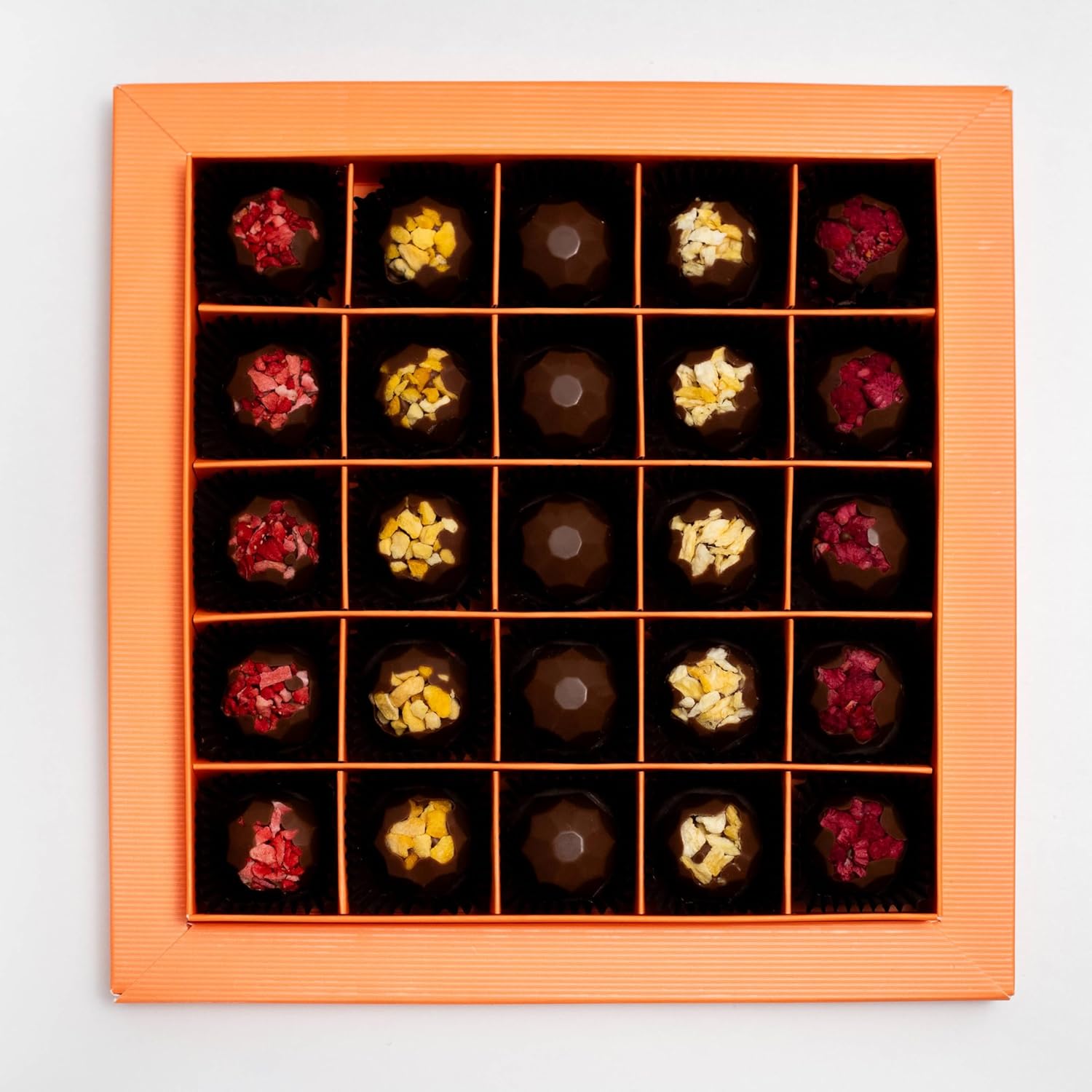 Assorted chocolates in a decorative wooden box on a light gray background