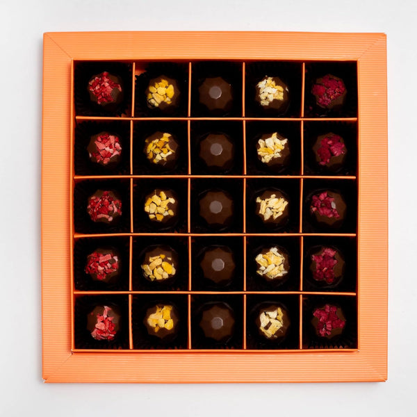 Assorted chocolates in a decorative wooden box on a light gray background