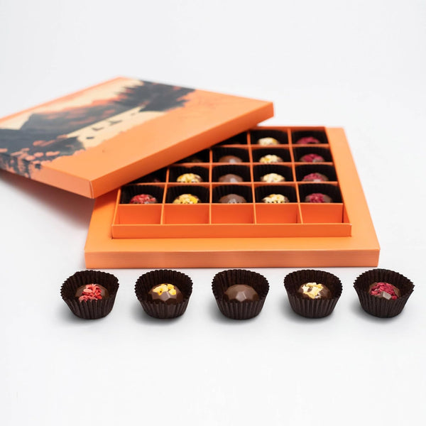 Open orange chocolate box with assorted chocolates on a white background