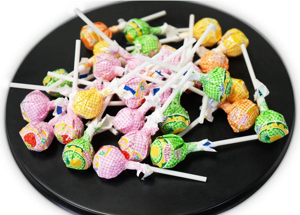 Colorful lollipops on sticks arranged on a black plate