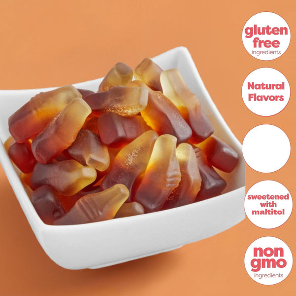 White bowl filled with gummy bears on an orange background with text indicating gluten-free, natural flavors, sweetened with maltitol, and non-gmo ingredients. Enjoy the bold, nostalgic taste of Andy Anand’s Sugar-Free Cola Gummies. Handcrafted in Europe, these 38 chewy mini bottles are gluten-free and diabetic-friendly. The perfect guilt-free gift for movie nights and parties!