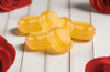 Yellow jelly candies on a white wooden surface with red flowers around