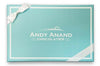 Blue gift box with white ribbon and 'Andy Anand Chocolatier' logo
