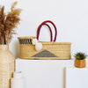Woven basket with red handles on a white surface with decorative elements.