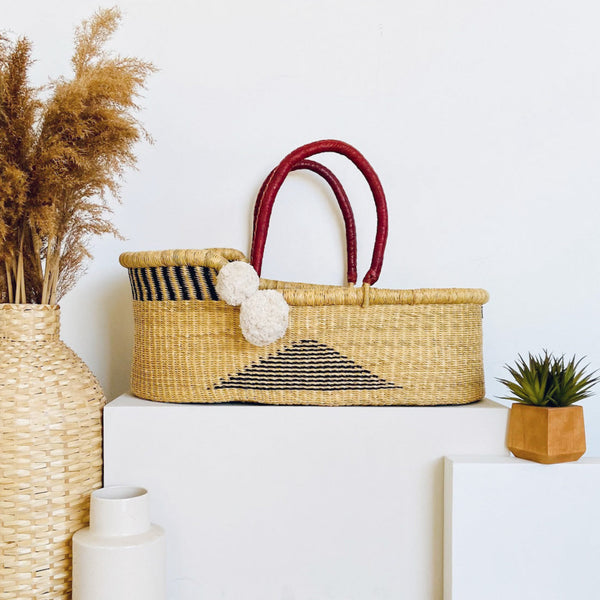 Woven basket with red handles on a white surface with decorative elements.