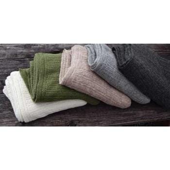 Three pairs of socks in white, green, and gray on a wooden surface