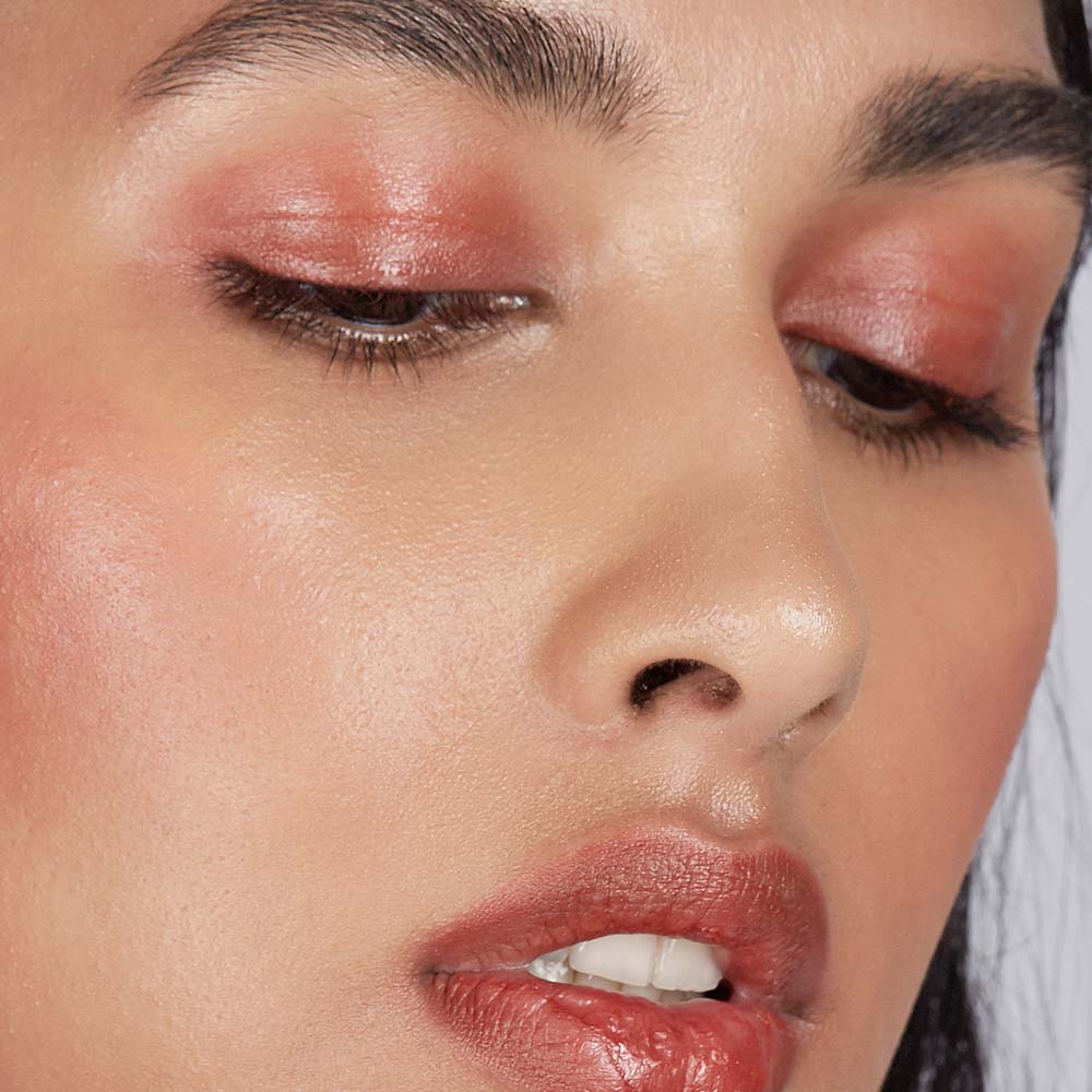Close-up of a woman's face with pink eyeshadow and lipstick.