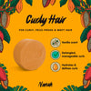 Bar of soap with vanilla scent for curly hair on a yellow background with cacao beans and leaves. NANAH Curly Hair conditioner bar — sulfate-free, defines & hydrates curls with vegetable keratin, castor oil & jojoba. Curly Girl Method approved. Shop now.