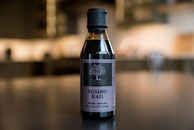 Bottle of Lichens Balsamic Glaze on a wooden surface with a blurred background