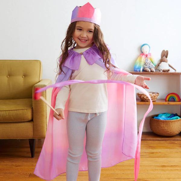 Child in a pink and purple costume with a rainbow-colored toy in the background