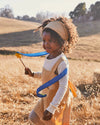 Child in a field holding a blue ribbon and flower