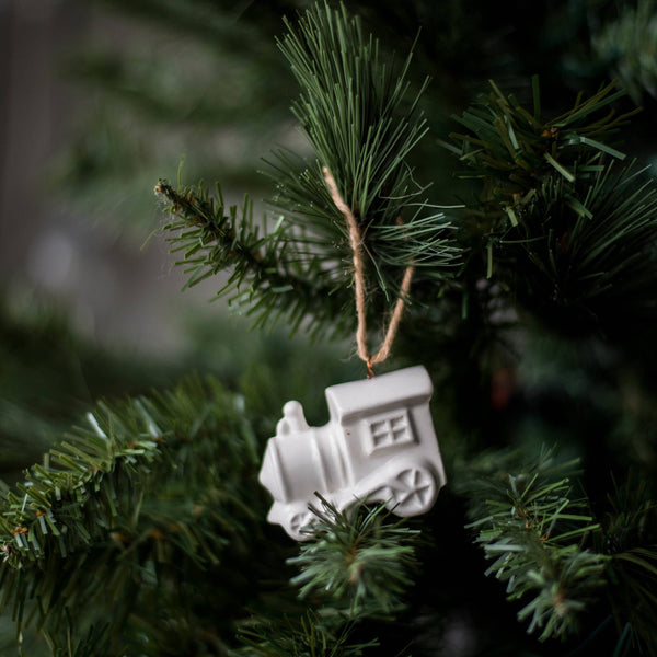 White train ornament hanging on a green Christmas tree