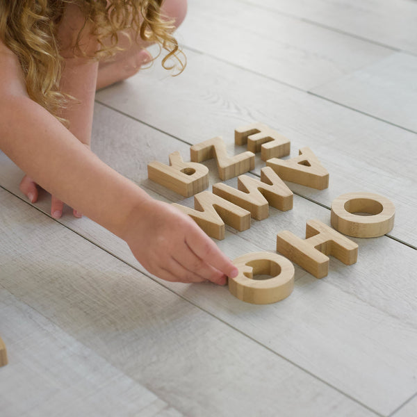 Child playing with bamboo alphabet learning toy, exploring letter shapes and spelling