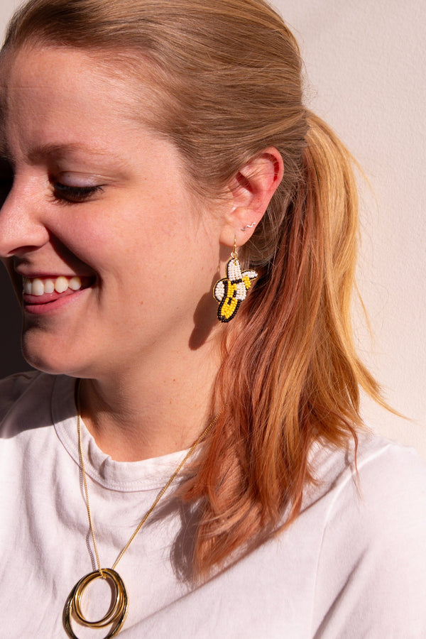 Close-up of beaded banana earrings showing one peeled and one whole banana motif, handmade by artisans