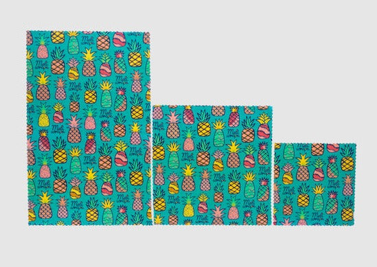 Set of three colorful towels with pineapple pattern on a light gray background