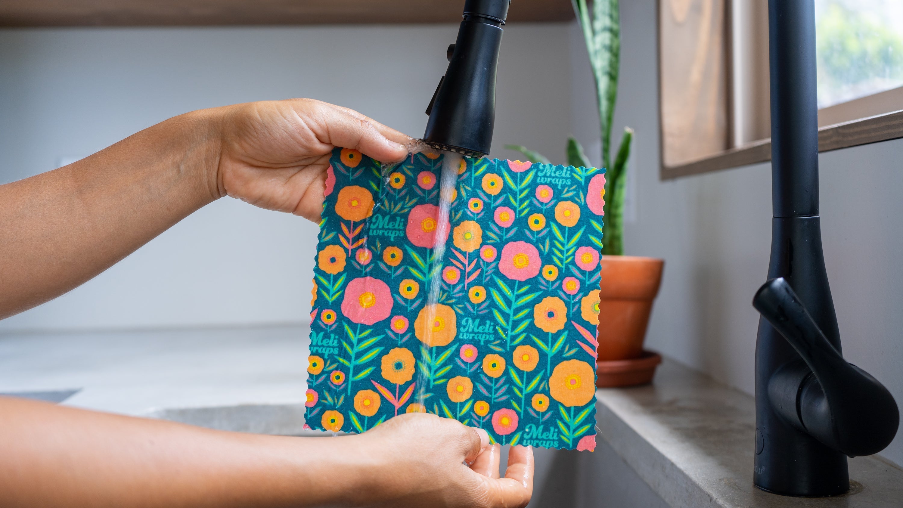 Meli Wraps beeswax food wrap being washed with cool water and mild dish soap