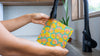 Person holding a colorful patterned pouch with a vacuum cleaner in the background