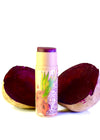 Lip balm with a colorful label next to two beet halves on a white background