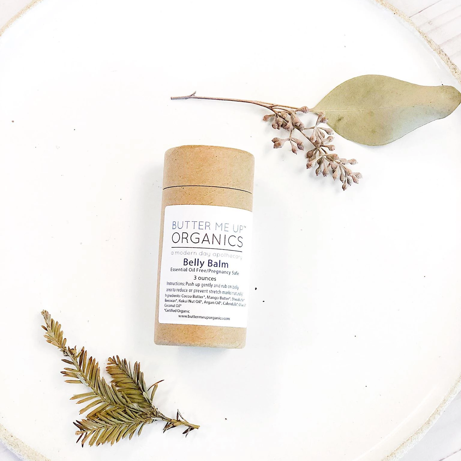 Butter Me Up Organics belly balm on a white plate with green leaves