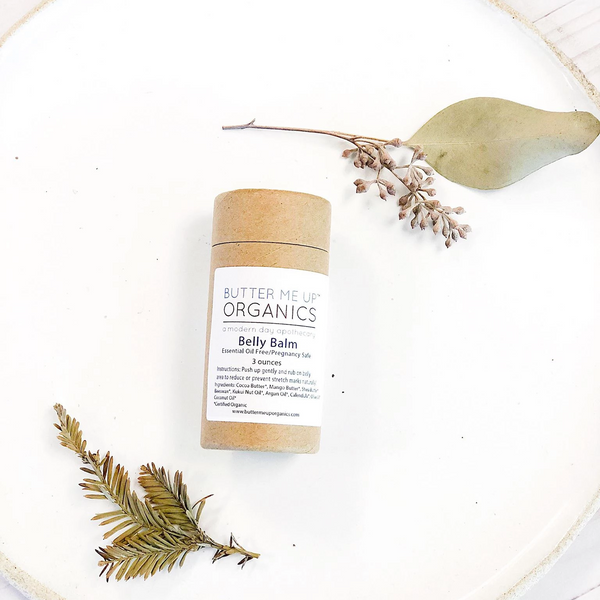 Butter Me Up Organics belly balm on a white plate with green leaves