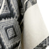 Close-up of textured fabric with geometric pattern and plain white fabric.