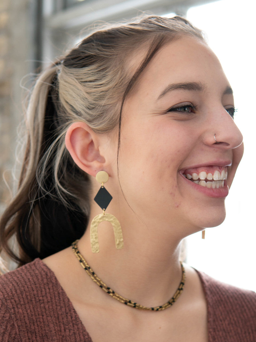 Close-up of black and gold geometric arch earrings on model, Fair Anita