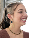 Close-up of black and gold geometric arch earrings on model, Fair Anita