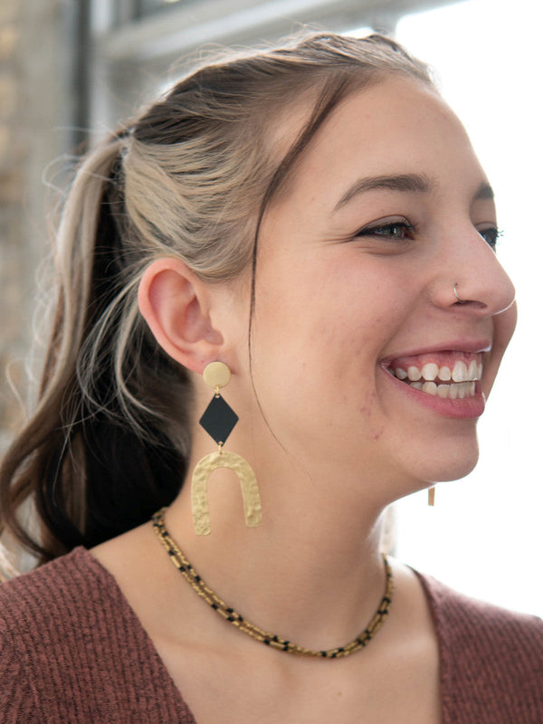 Close-up of black and gold geometric arch earrings on model, Fair Anita