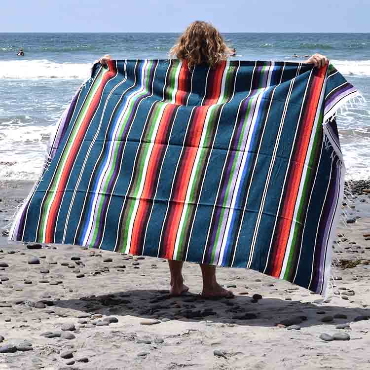 Person holding a colorful striped towel on a beach